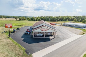 A motel with a parking lot, a signboard, and a building with a flat roof. - Capital O Aurora Inn Monett US 60 (Aurora)