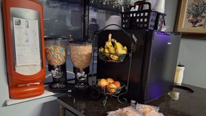 A kitchen counter with a blender, a fruit basket, and a plate of bread. - Capital O Aurora Inn Monett US 60 (Aurora)