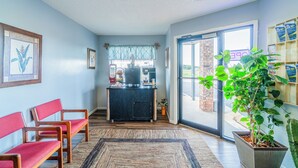 A reception area with a desk, chairs, a potted plant, and a view through a glass door. - Capital O Aurora Inn Monett US 60 (Aurora)