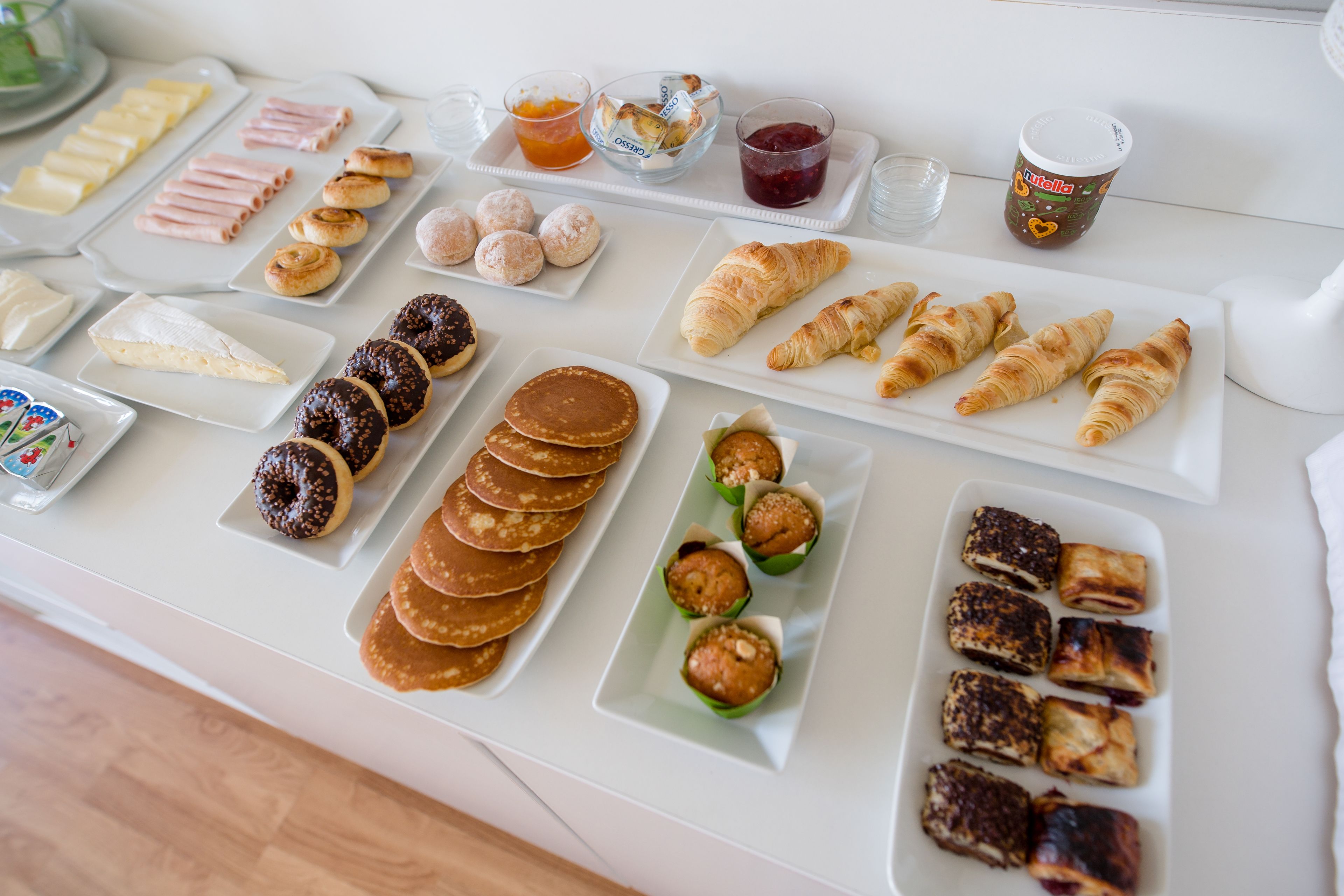 En morgenmadsbuffet med forskellige kager, bagværk og drikkevarer.