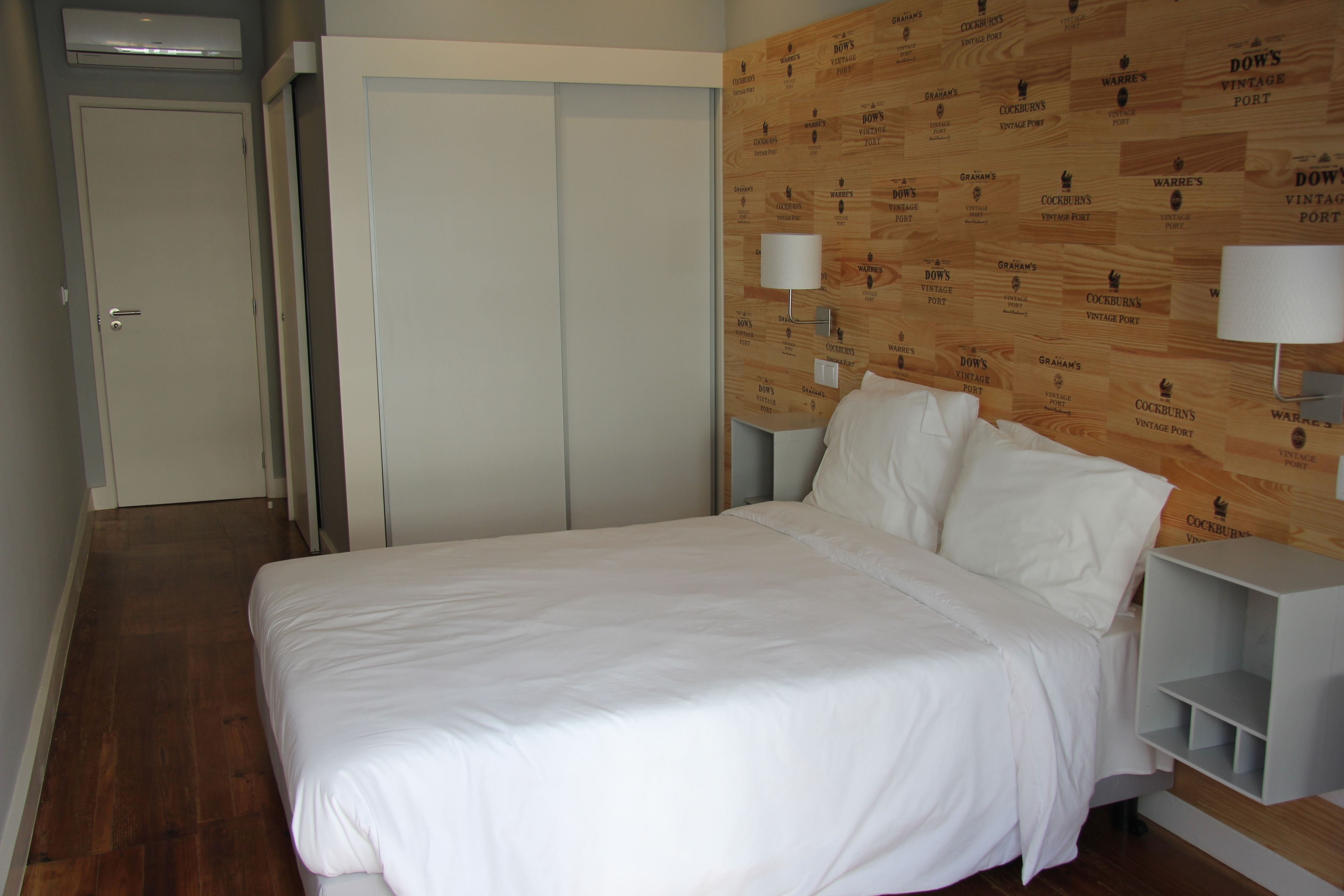 A bedroom with a wooden headboard, a white bed, and two bedside tables with lamps.