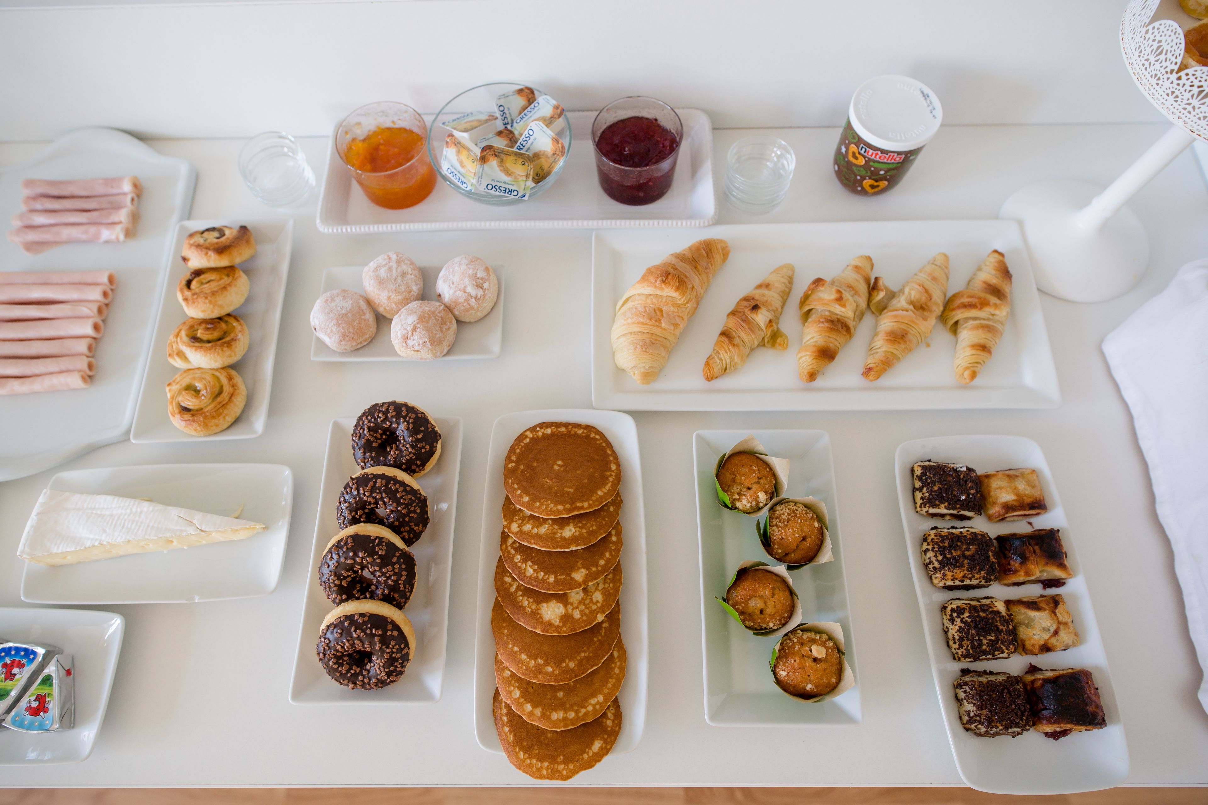 A breakfast buffet with various pastries, donuts, and beverages.