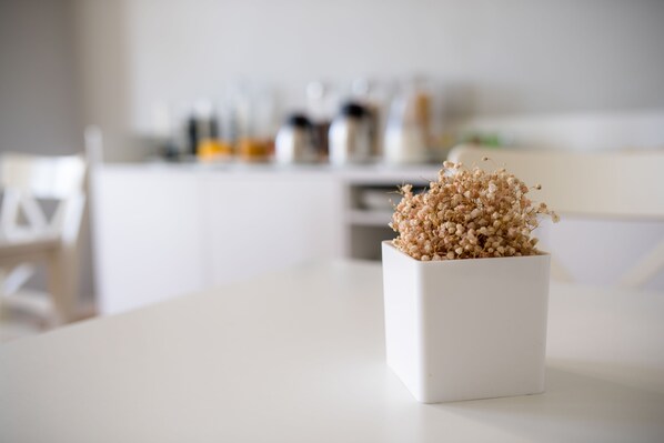 A white table with a square vase containing dried flowers. - Decanting Porto House (Porto)