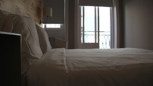Hotelkamer met een groot bed, een nachtkastje en een raam met uitzicht op een balkon.