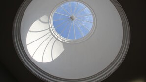 Een rond dakvenster met een centraal glasplaatje en uitstralende balken.