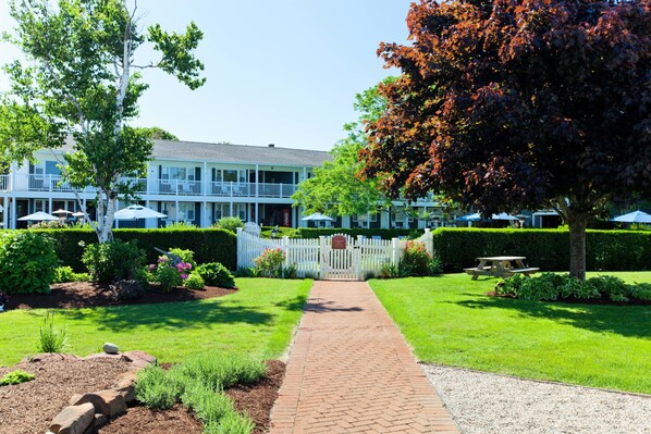 A well-maintained garden with a paved walkway leading to a building with multiple windows and balconies.