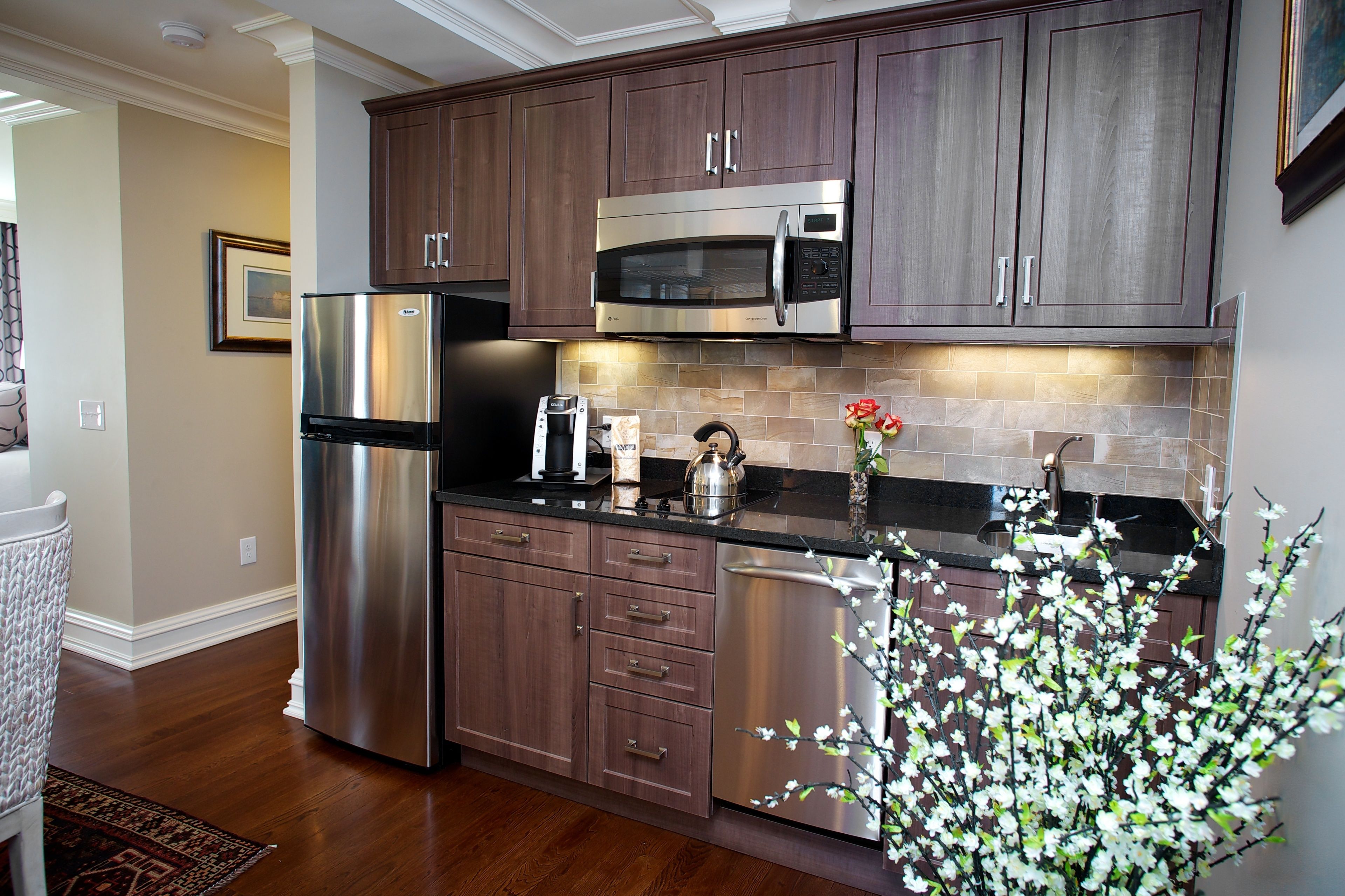 A modern kitchen with stainless steel appliances, dark wooden cabinets, and a tiled backsplash.