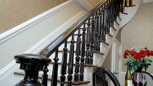 A staircase with dark wooden balusters and a white wall with a decorative molding. - Guesthouse at Norwalk Inn (Norwalk)