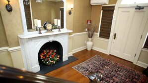 A grand hallway with a white fireplace, a large mirror, and a floral arrangement. - Guesthouse at Norwalk Inn (Norwalk)