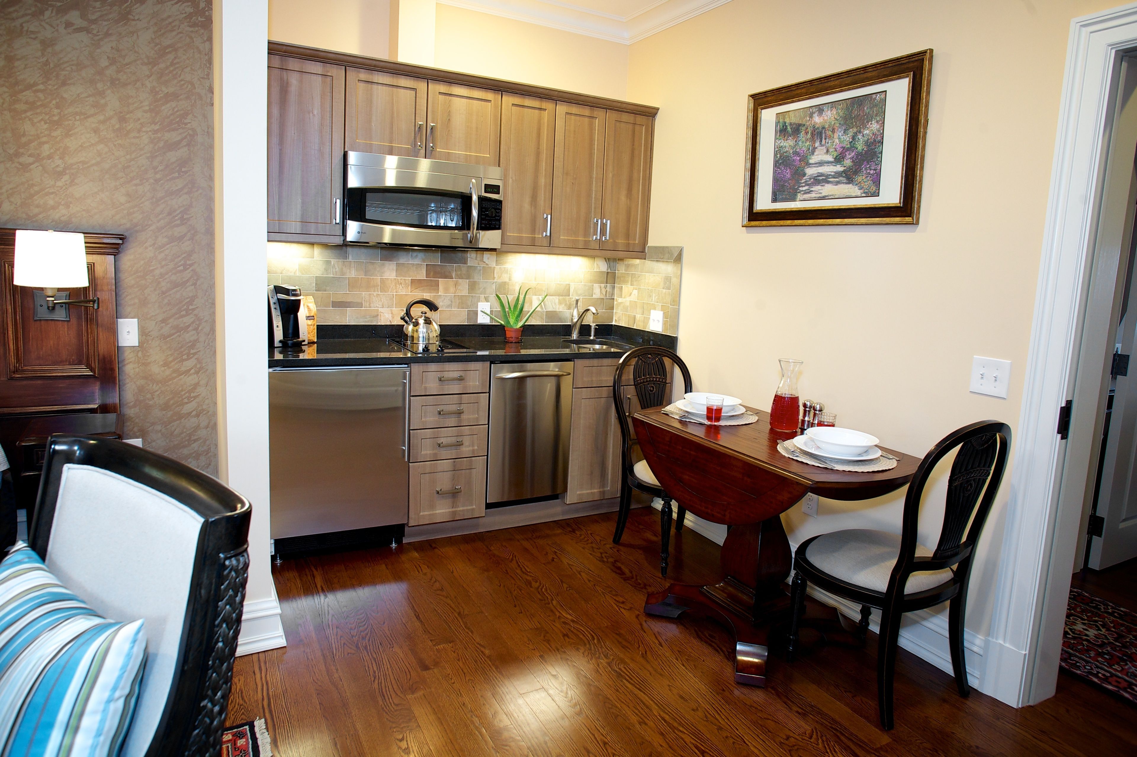 A kitchen with wooden cabinets, stainless steel appliances, and a dining area with a table and chairs.