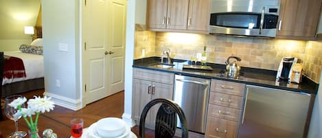 A modern kitchen with stainless steel appliances, wooden cabinets, and a dining area with a table set for two.