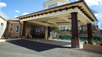 A hotel entrance with a covered walkway, large columns, and a clear sky.