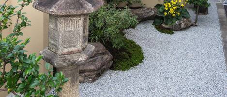 A garden with a stone lantern, gravel path, and various plants.