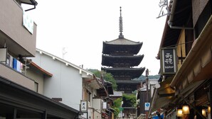 Una calle estrecha con edificios tradicionales y una pagoda a lo lejos.