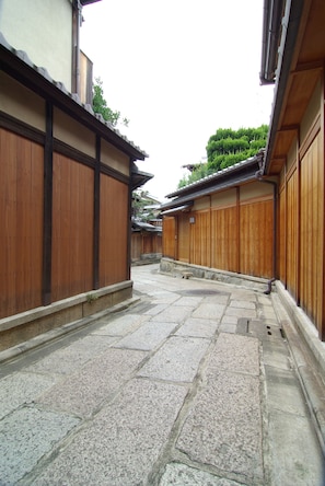 Une cour intérieure de style japonais traditionnel, avec des murs en bois et un sol pavé de pierres.