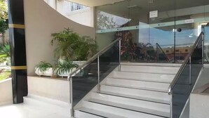 A staircase with glass railings leading to a building entrance. - Sayuri Hotel (Foz do Iguaçu)