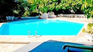 A rectangular swimming pool with a clear blue water surface, surrounded by a tiled deck. - Sayuri Hotel (Foz do Iguaçu)