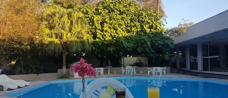 Una piscina al aire libre, sillones reclinables de piscina