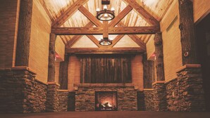 Une cheminée en pierre avec une cheminée en bois, un plafond en bois avec des poutres apparentes et un mur en pierre sur un des côtés.