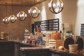 A bar area with hanging spherical chandeliers, a wooden counter, and a menu board in the background.