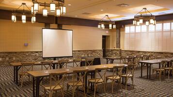 A conference room with a whiteboard, tables, chairs, and a stone wall.