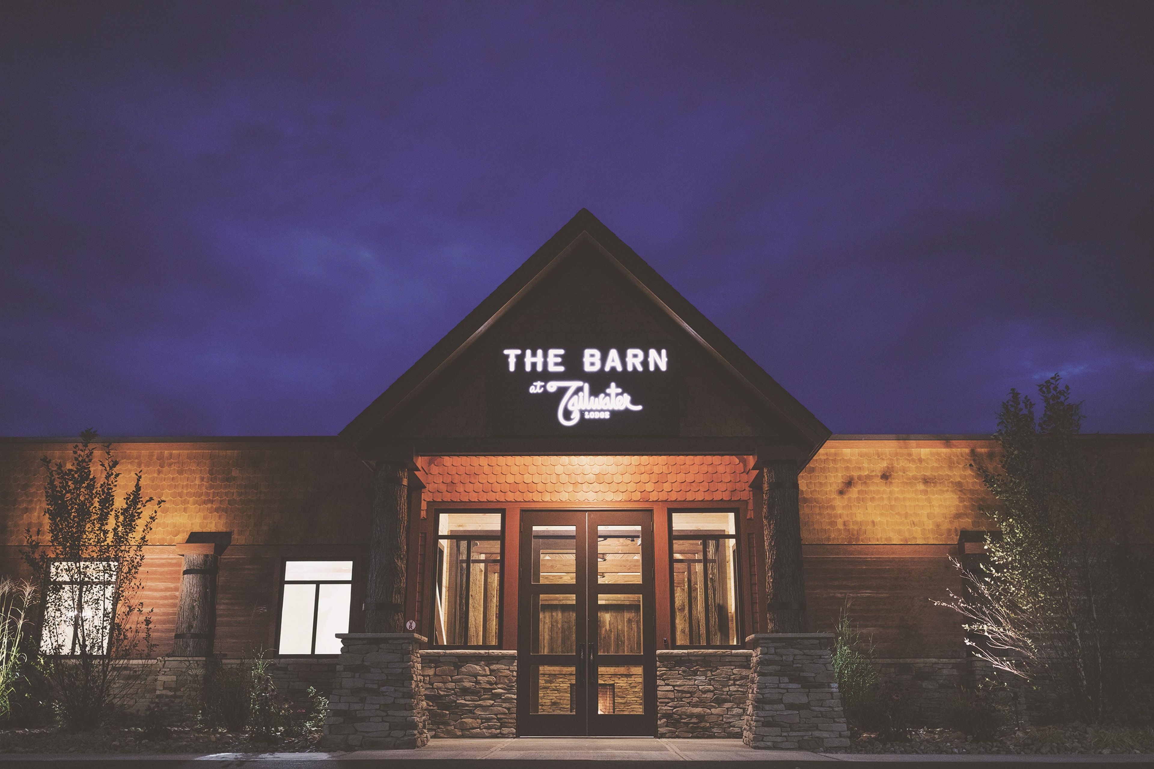 A building with a sign reading 'THE BARN at Gilwater LODGE' at night.