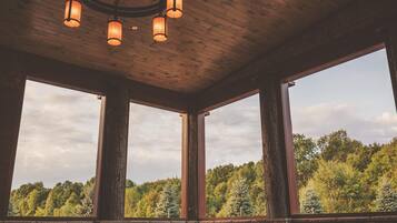 A room with a stone wall, large windows, and a wooden ceiling with hanging lights.