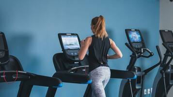 Eine Frau läuft auf einem Laufband in einem Fitnessstudio mit blauen Wänden und mehreren Laufbändern.