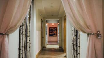 A hallway with a door at the end leading to a room.