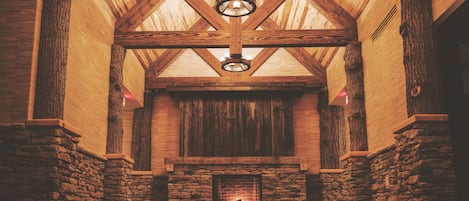 A stone fireplace with a wooden ceiling and a hanging light fixture.