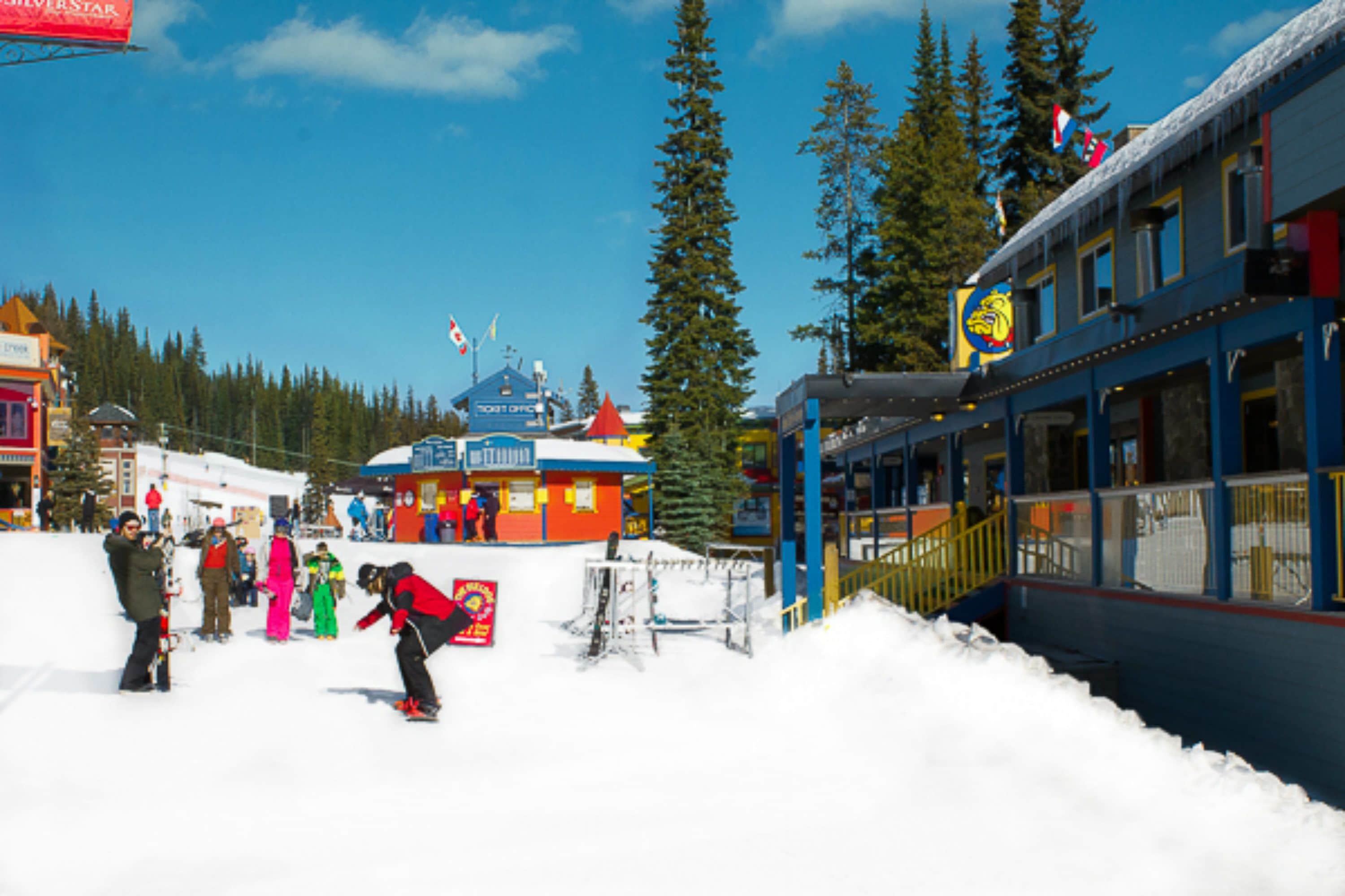 A ski resort with a colorful building, a ski lift, and snow-covered ground.