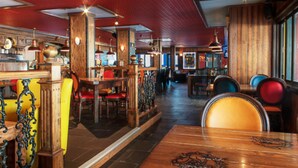 A restaurant interior with wooden tables, chairs, and a red ceiling.