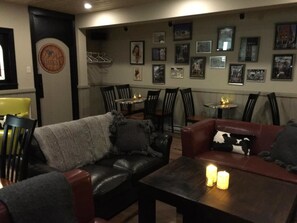 A cozy lounge area with leather sofas, a coffee table with candles, and a wall adorned with framed pictures. - The Bulldog Hotel Silver Star (Silver Star Mountain)