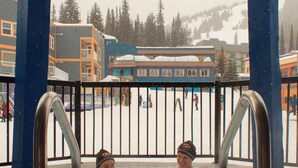A hot tub area with metal railings and a view of a snowy outdoor scene with buildings and people.