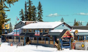 A building with a snow-covered roof, a sign for SilverStar, and a flag. - The Bulldog Hotel Silver Star (Silver Star Mountain)