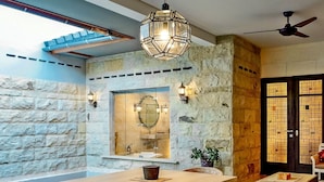 A modern interior with a stone wall, a wooden dining table, and a pool. - Alindra Villas & Spa (Jimbaran)