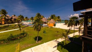 Een resort met rieten bungalows, een zwembad en een strand.