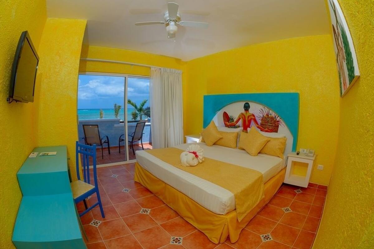 A hotel room with a bed, a desk, and a view of the ocean.