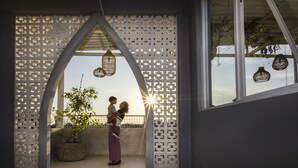 A couple embracing in a room with a decorative lattice partition, a potted plant, and hanging lanterns. - Cozy Stay (Denpasar)