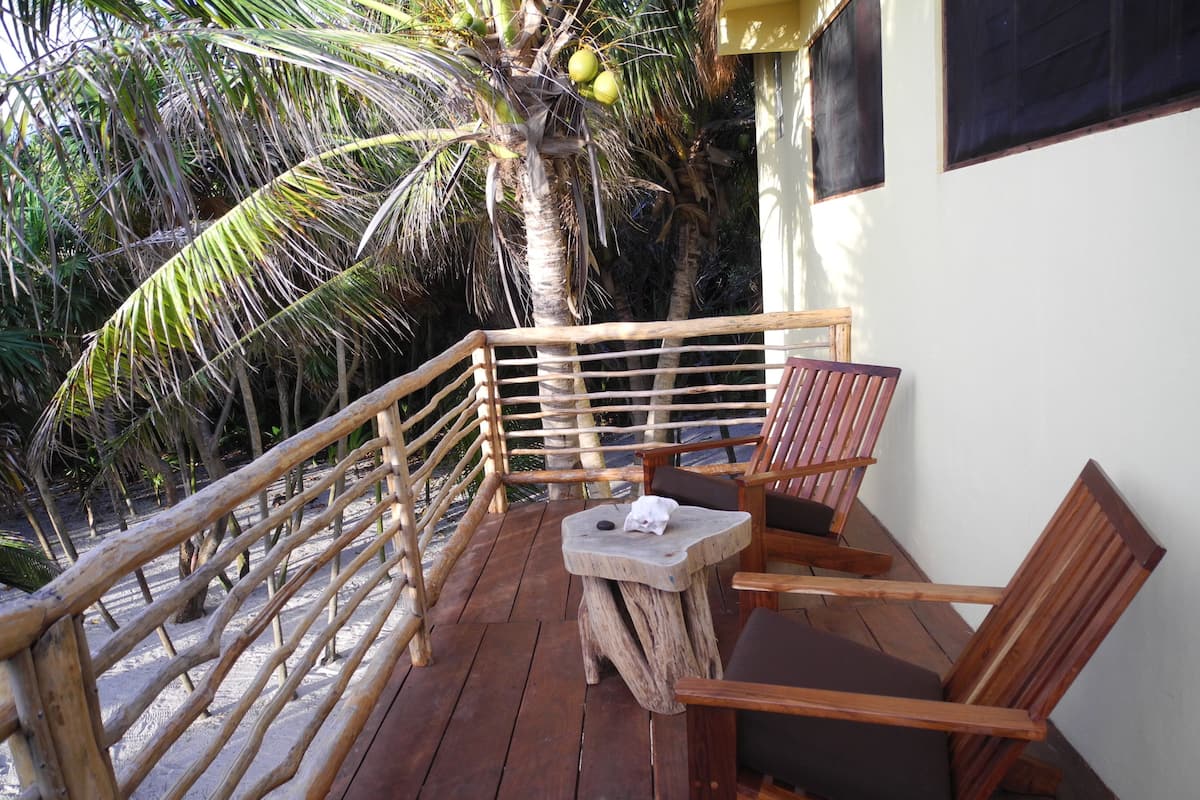 A wooden deck with a railing, a table, and two chairs.