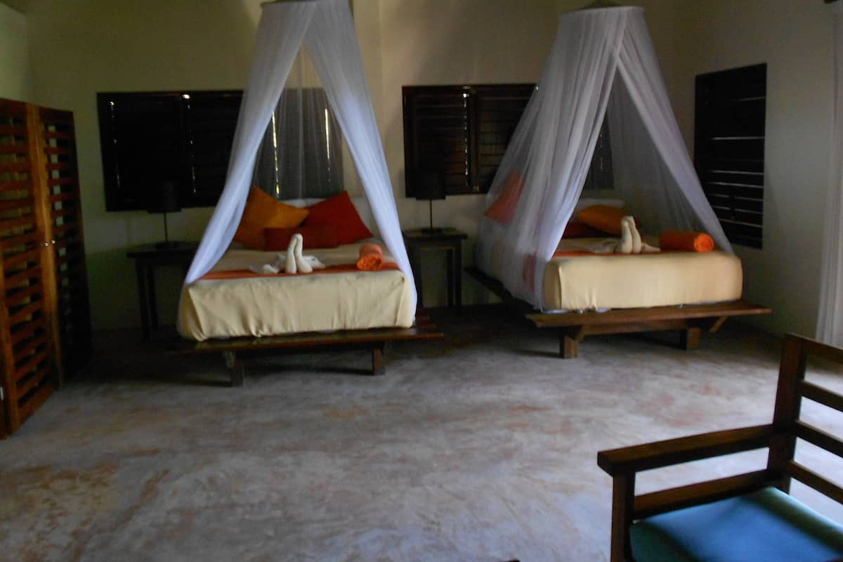 Two single beds with canopy beds, a wooden bench, and a tiled floor.