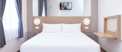 A modern hotel room with a large bed, a headboard with integrated lighting, a bedside table, and a wall-mounted shelf.