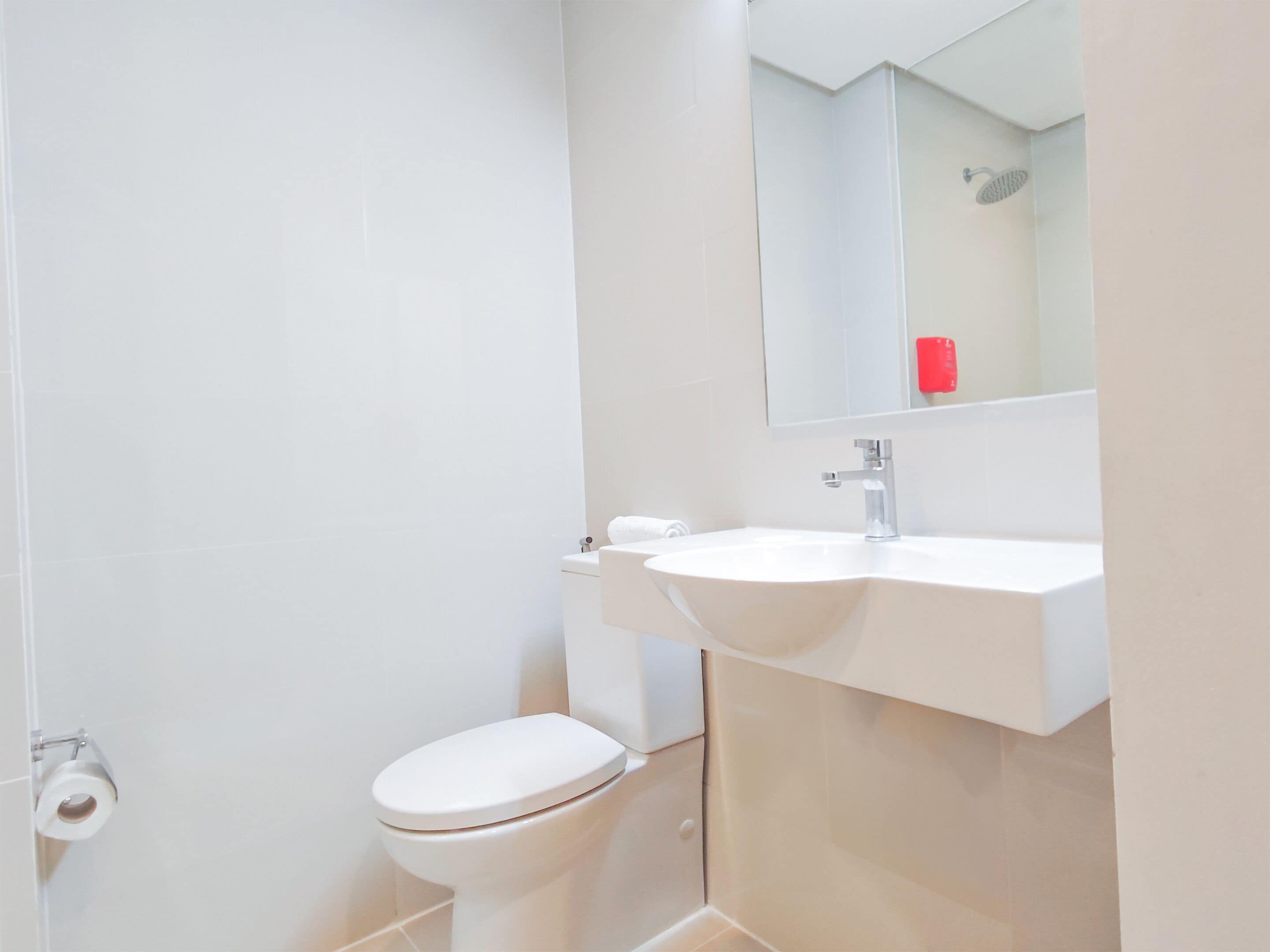 A modern bathroom with a toilet, sink, and mirror.