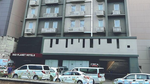 A multi-story hotel with balconies, a parking area, and a sign for Red Planet Hotels. - Red Planet Cagayan De Oro (Cagayan de Oro)