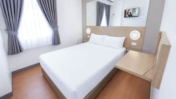 Una habitación de hotel moderna con una cama grande, una mesita de noche, un espejo y una ventana con cortinas.