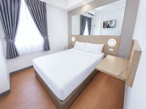 A modern hotel room with a large bed, a bedside table, a mirror, and a window with curtains. - Red Planet Cagayan De Oro (Cagayan de Oro)