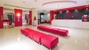 A reception area with a red and white color scheme, multiple red seating areas, and a reception desk with staff. - Red Planet Cagayan De Oro (Cagayan de Oro)
