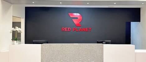 Una mesa de recepción con el logotipo de Red Planet y un letrero de Cagayan de Oro.