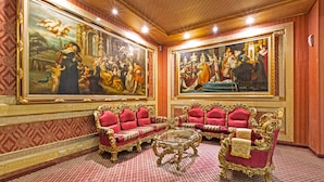 A luxurious room with ornate red and gold furniture, large classical paintings on the walls, and a patterned carpet. - The We Hotel (Taipei)