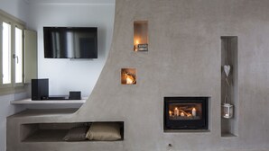 A modern living room with a television, fireplace, and built-in shelving. - Melograno Villas (Astypalaia)